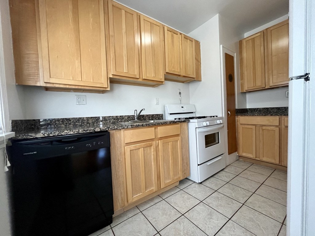 an empty kitchen with wooden cabinets and white appliances
