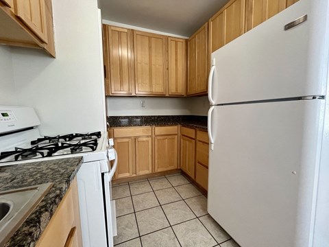 an empty kitchen with white appliances and wooden cabinets