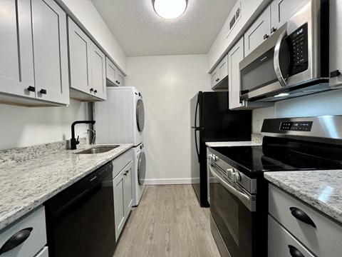 a kitchen with white cabinets and stainless steel appliances and a black refrigerator
