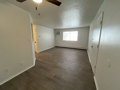 an empty living room with wood floors and a window
