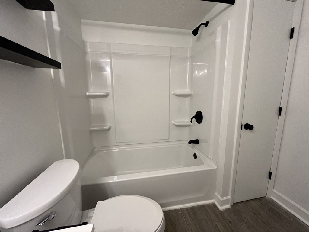 a white bathroom with a toilet and a tub