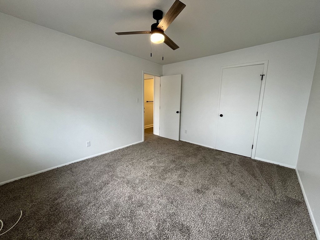 an empty living room with carpet and a ceiling fan