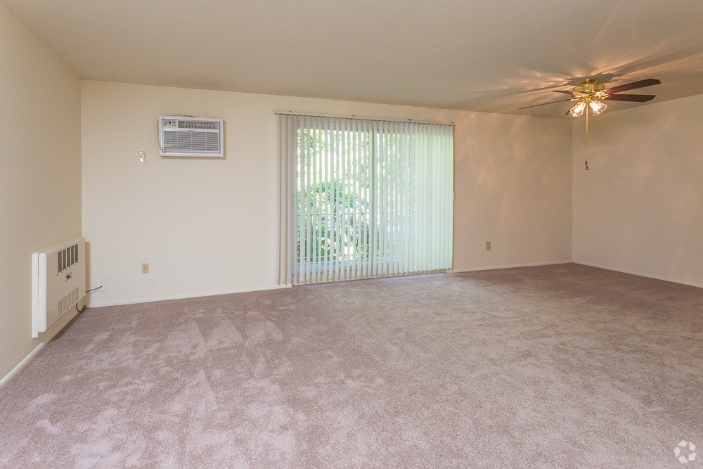 an empty living room with a ceiling fan and a window