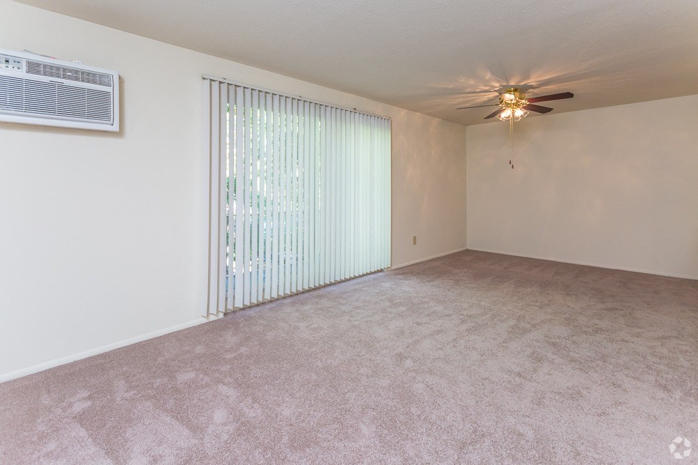 an empty living room with blinds and a ceiling fan