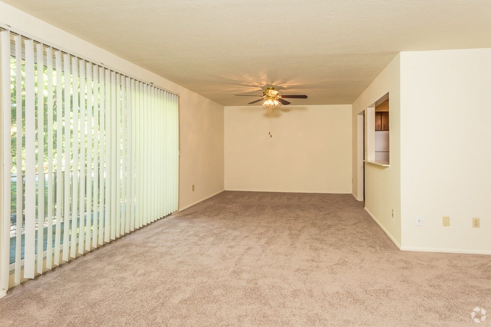 an empty living room with blinds and a ceiling fan