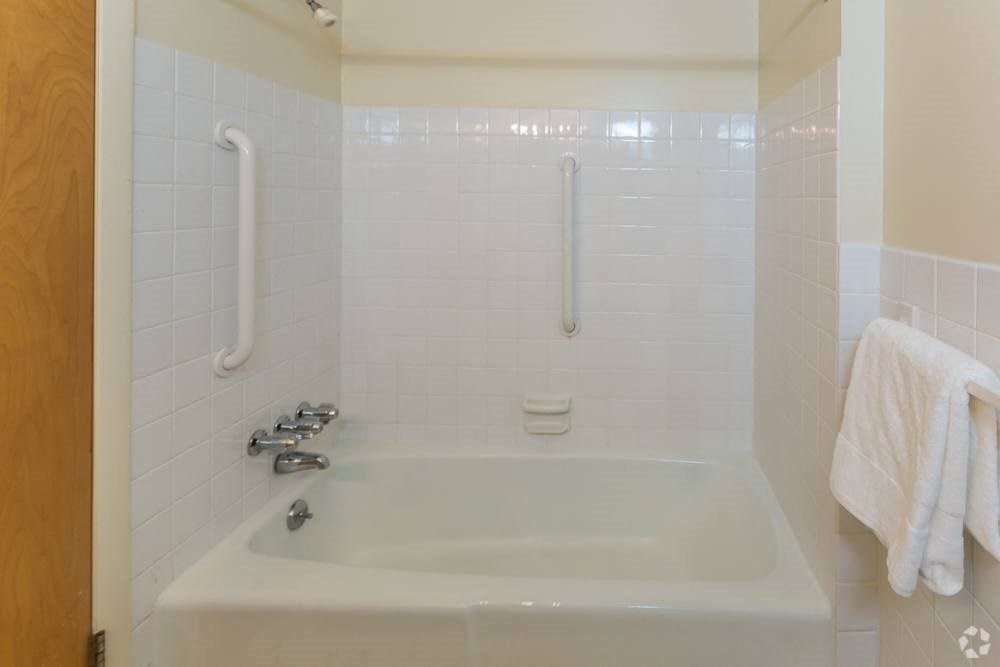 a white bath tub in a white tiled bathroom