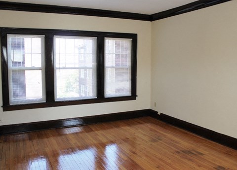 an empty room with wooden floors and three windows
