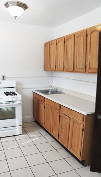 an empty kitchen with wooden cabinets and a stove and sink