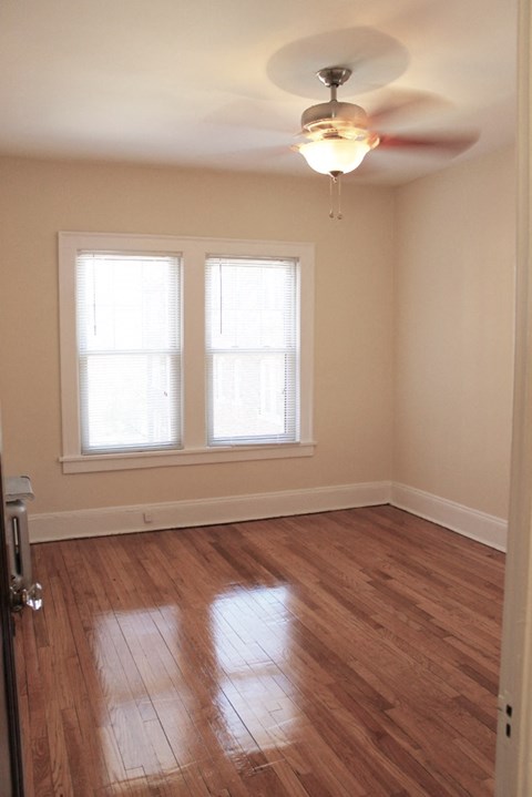an empty room with a ceiling fan and two windows