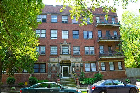the apartment building has two cars parked in front of it