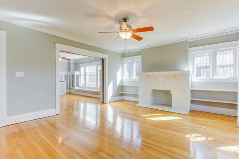 an empty living room with a fireplace and a ceiling fan