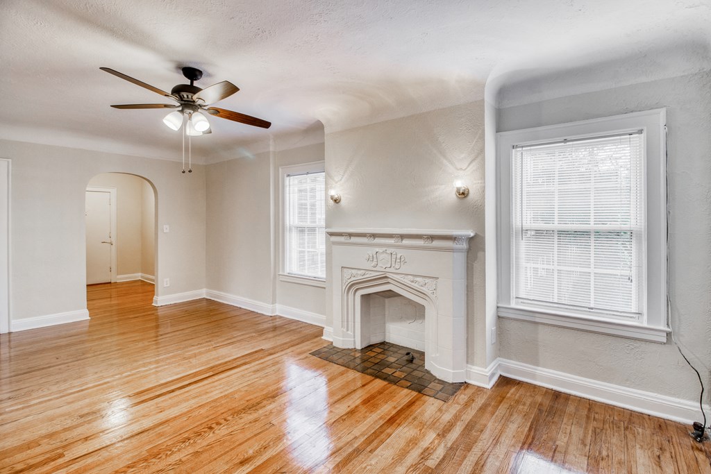 an empty living room with a fireplace and a ceiling fan
