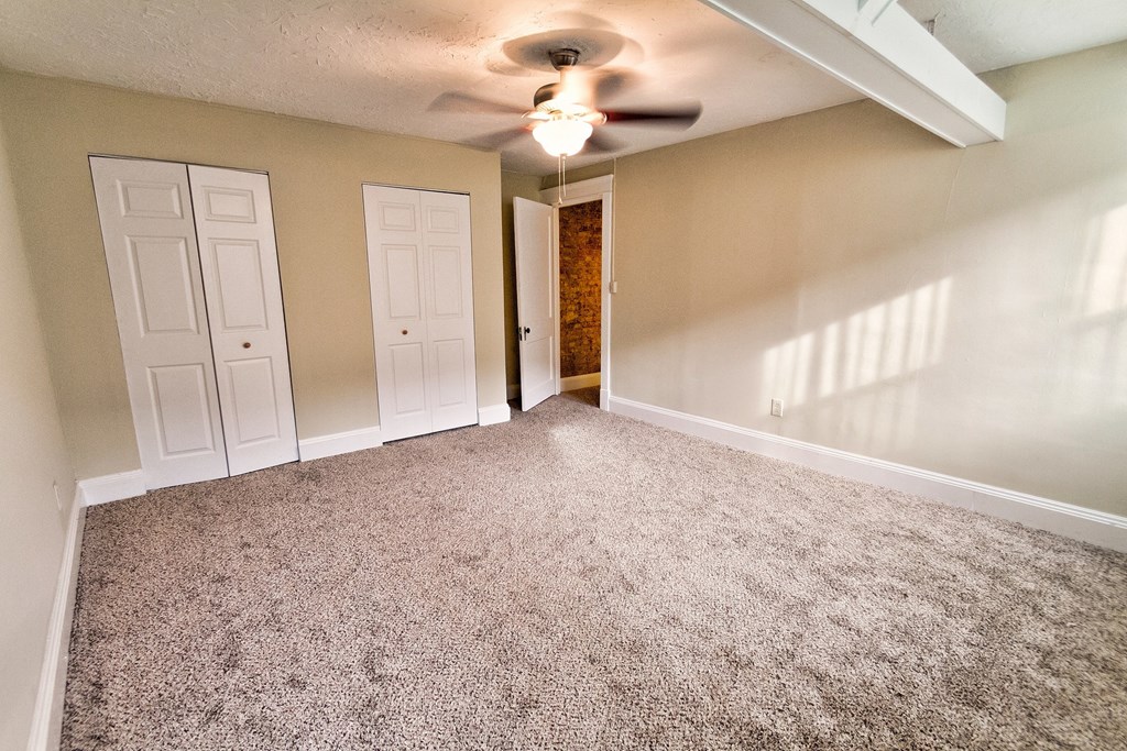 an empty living room with carpet and a ceiling fan