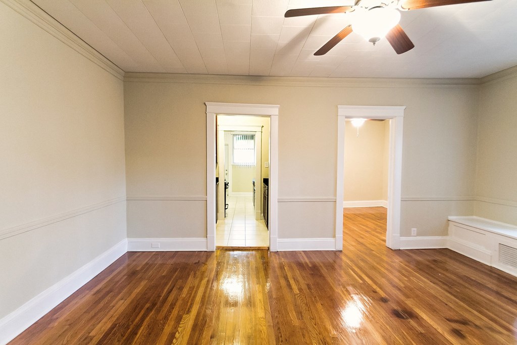 an empty living room with wood floors and a ceiling fan