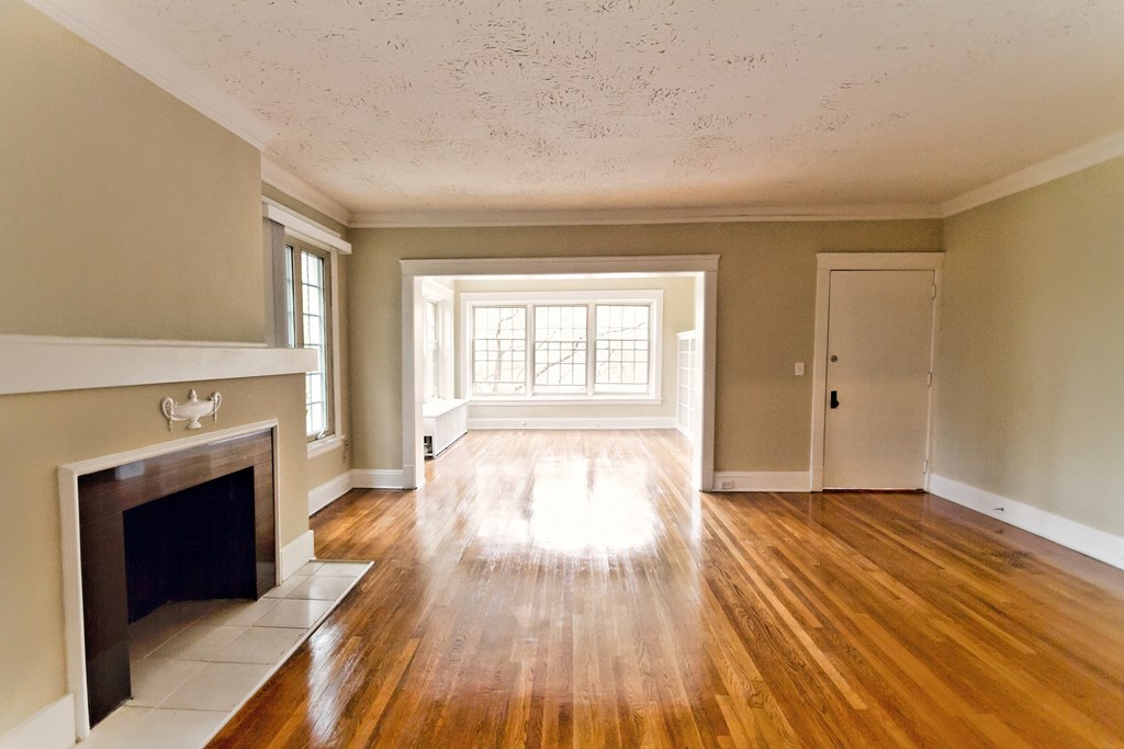 an empty living room with a fireplace and wooden floors