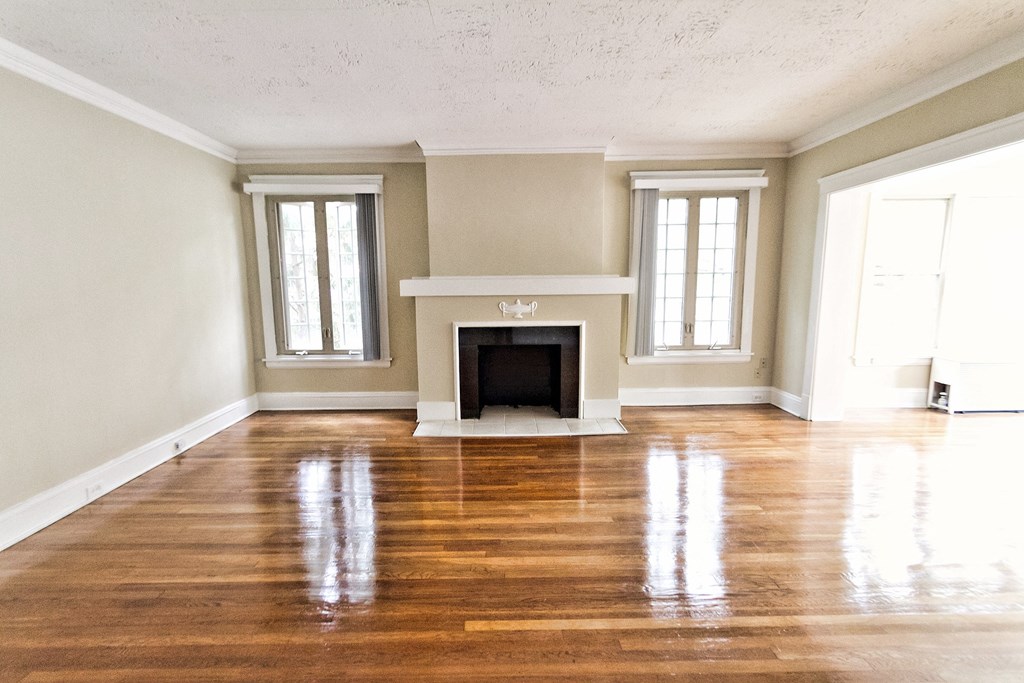 an empty living room with a fireplace and wooden floors