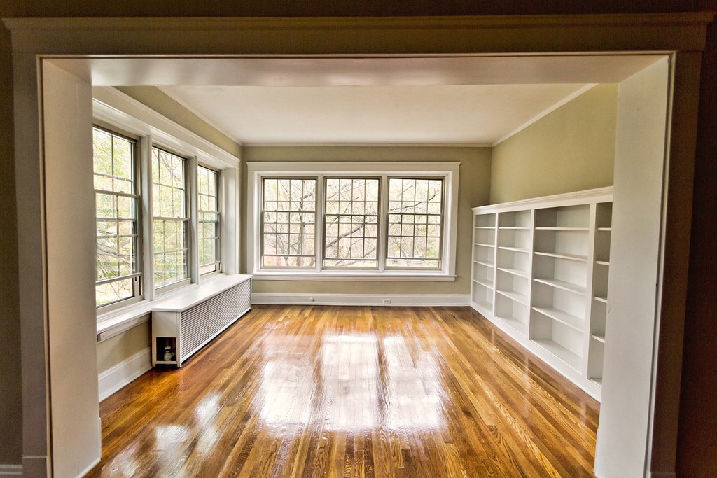 an empty living room with a large window and book shelves