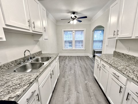 A kitchen with white cabinets and a marble countertop.
