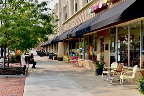 a city street with tables and chairs outside a store