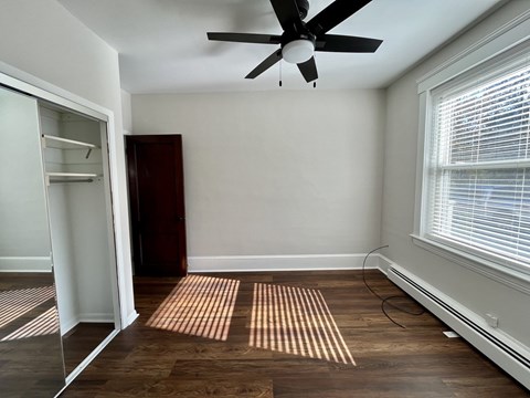 A room with a ceiling fan and a window with blinds.