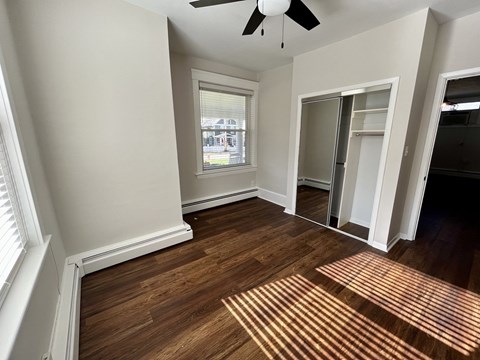 A room with a ceiling fan and wooden flooring.