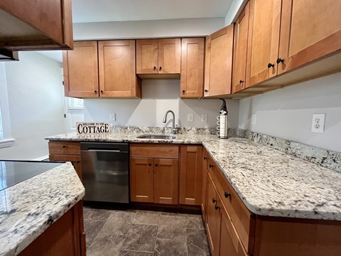 A kitchen with a granite counter top and wooden cabinets.
