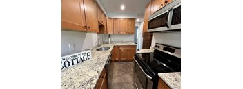 a cherry cabinet kitchen with granite counter tops and wooden cabinets