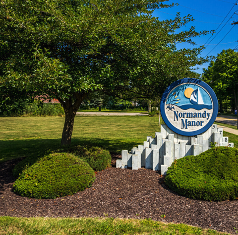a sign for the northwest manor mall in front of a tree