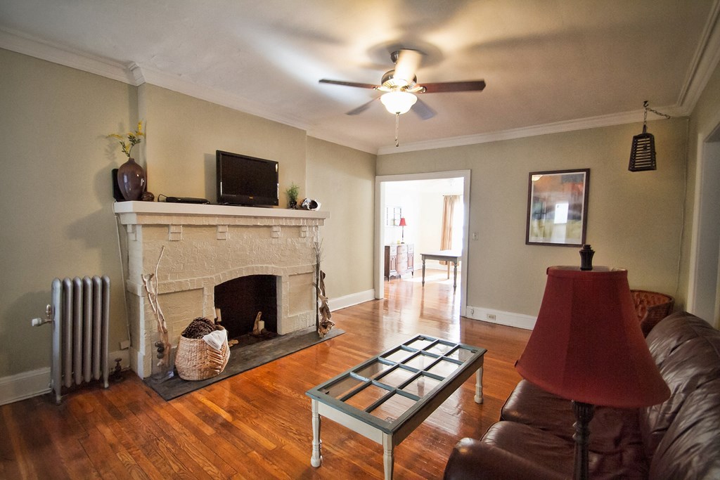 an empty living room with a fireplace and a ceiling fan