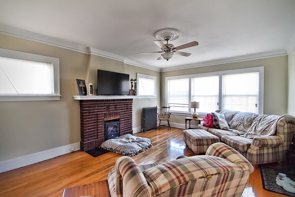 a living room with couches and a fireplace and a ceiling fan