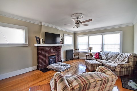 a living room with couches and a fireplace and a ceiling fan