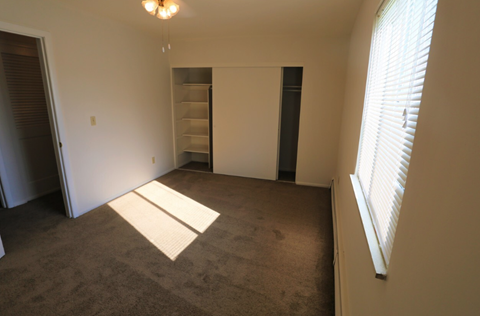 an empty room with a closet and a window