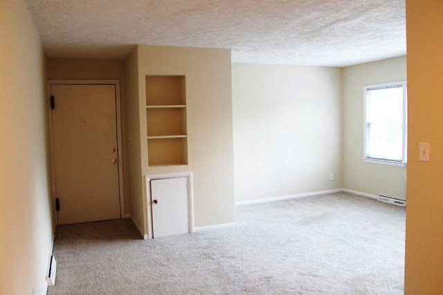 an empty living room with shelves and a door
