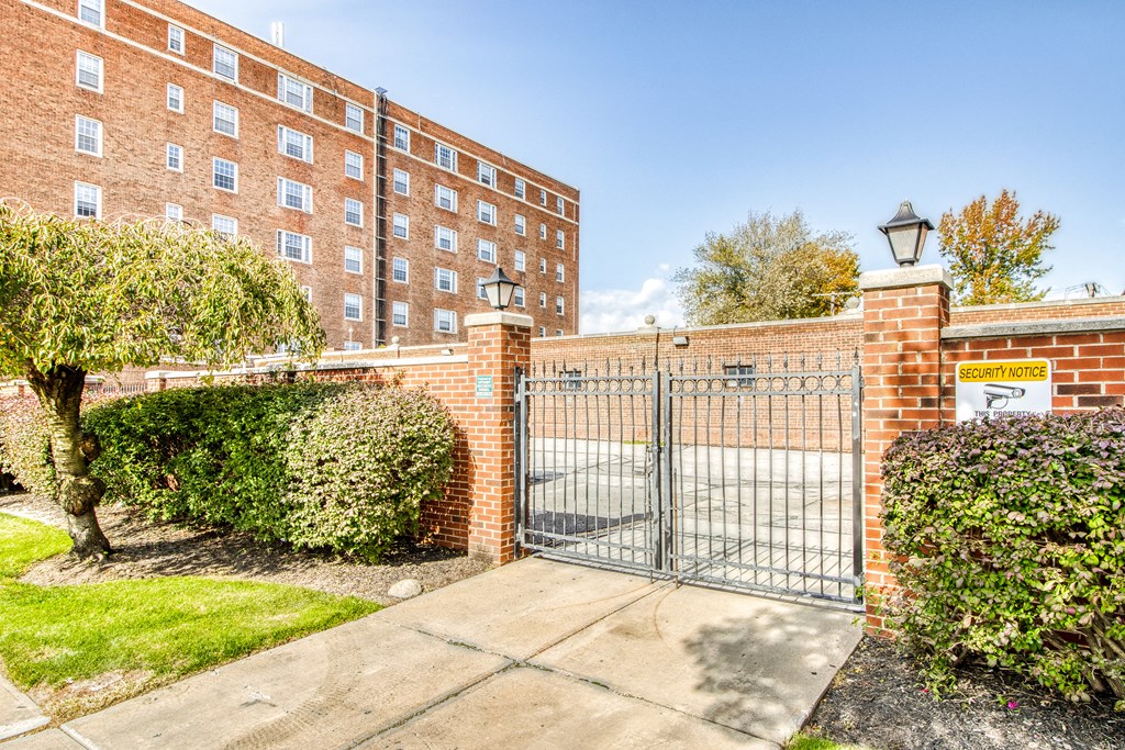 the gate to a gated parking lot with a brick building