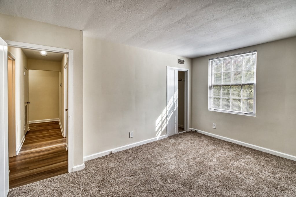 an empty living room with carpet and a window
