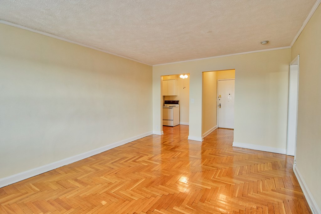 a spacious living room with wood flooring and white walls