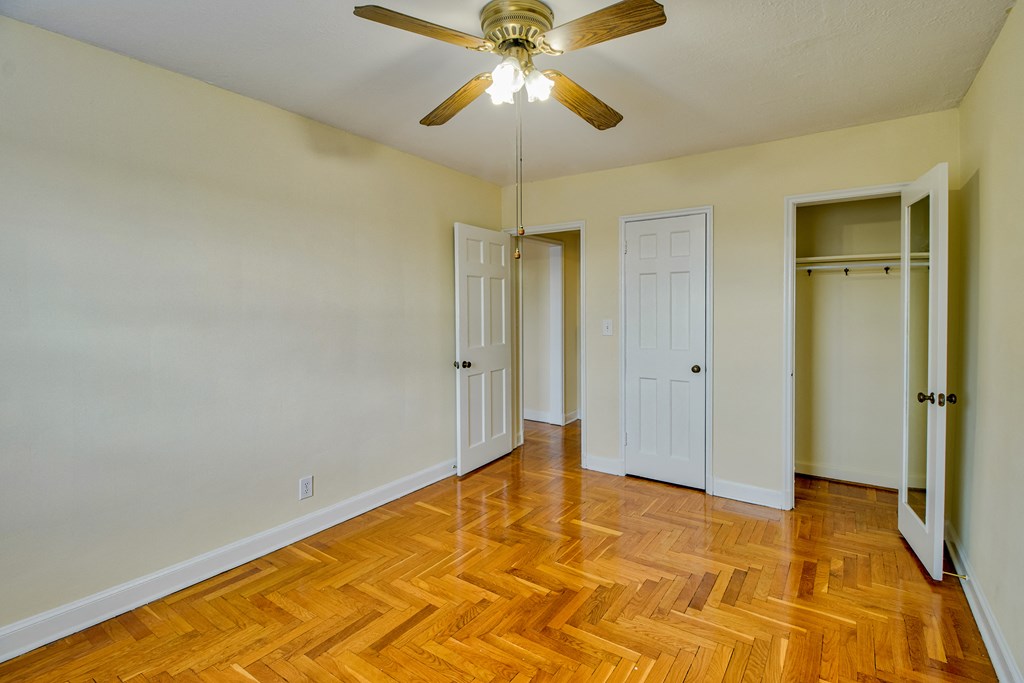 an empty living room with wood floors and a ceiling fan