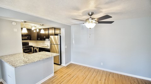 an empty living room with a ceiling fan and a kitchen
