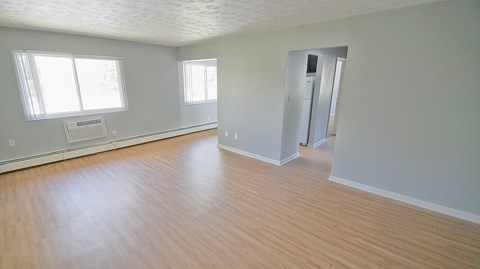 an empty living room with wood flooring and a door to a hallway