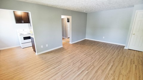 an empty living room and kitchen with wood flooring