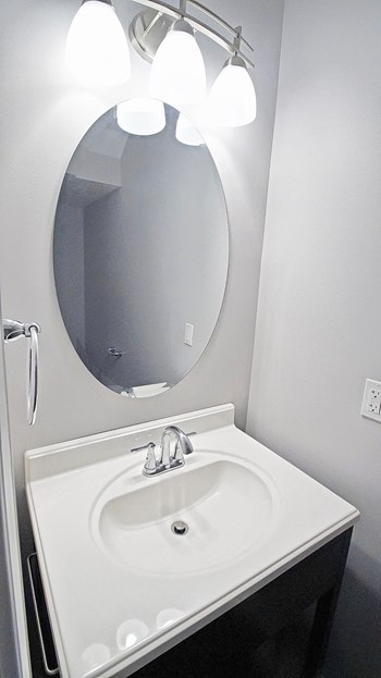 Master bathroom with floating vanities, quartz countertops, backlit vanity mirror, walk-in shower with Euro shower door and quartz-topped bench seat Master bathroom with floating vanities at The Reserves at 1150 Apartments, Integrity Realty LLC, Parma, 44134 - Photo Gallery 6