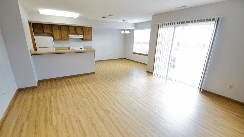 an empty living room and kitchen with wood flooring