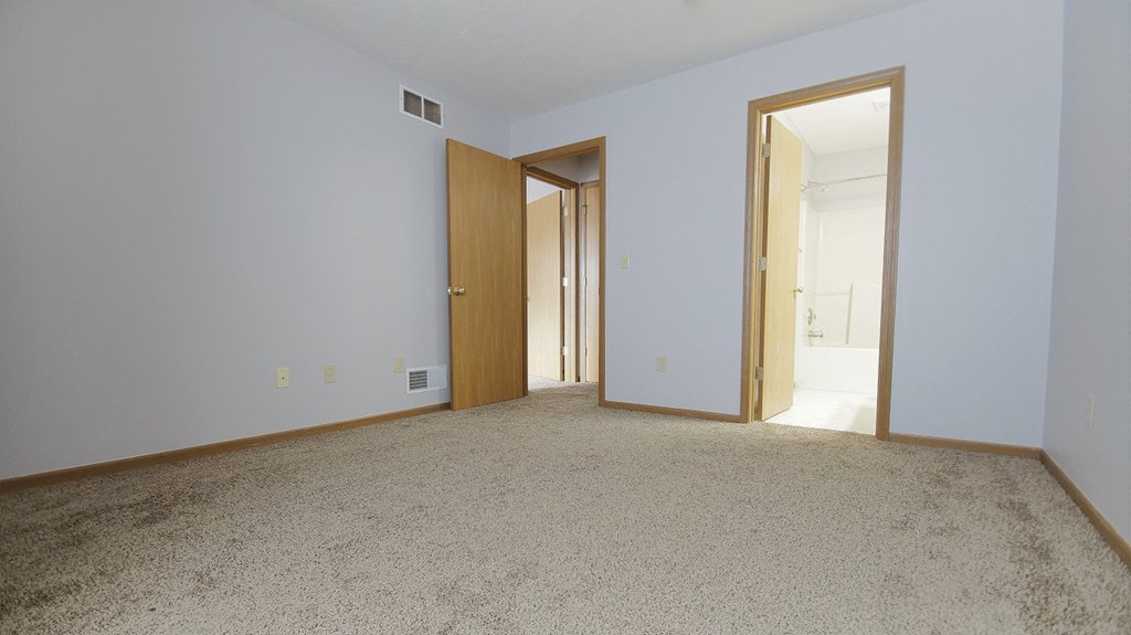 an empty living room with an open door to a bedroom
