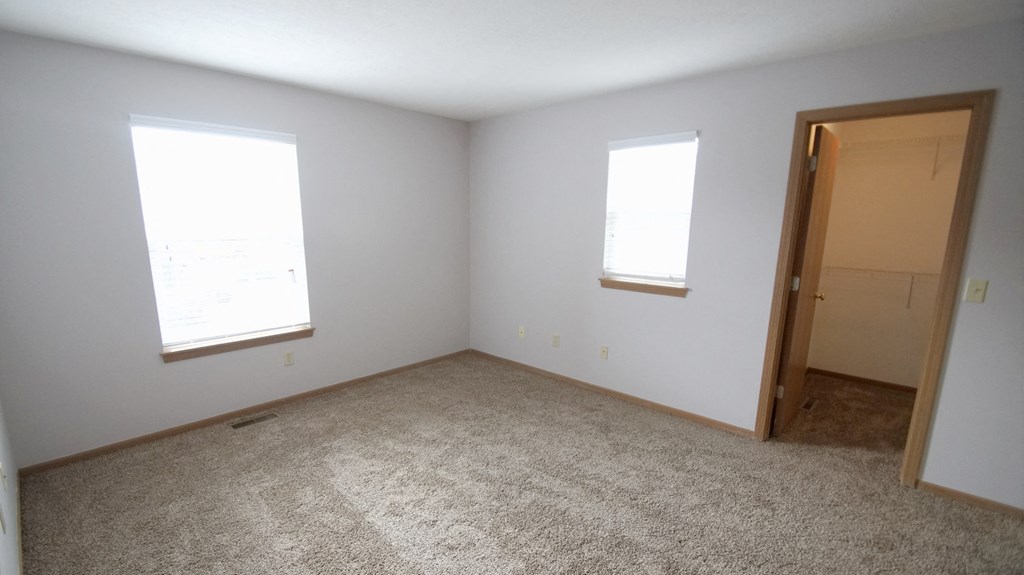 an empty room with two windows and a door