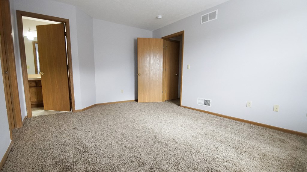 an empty living room with carpet and two doors