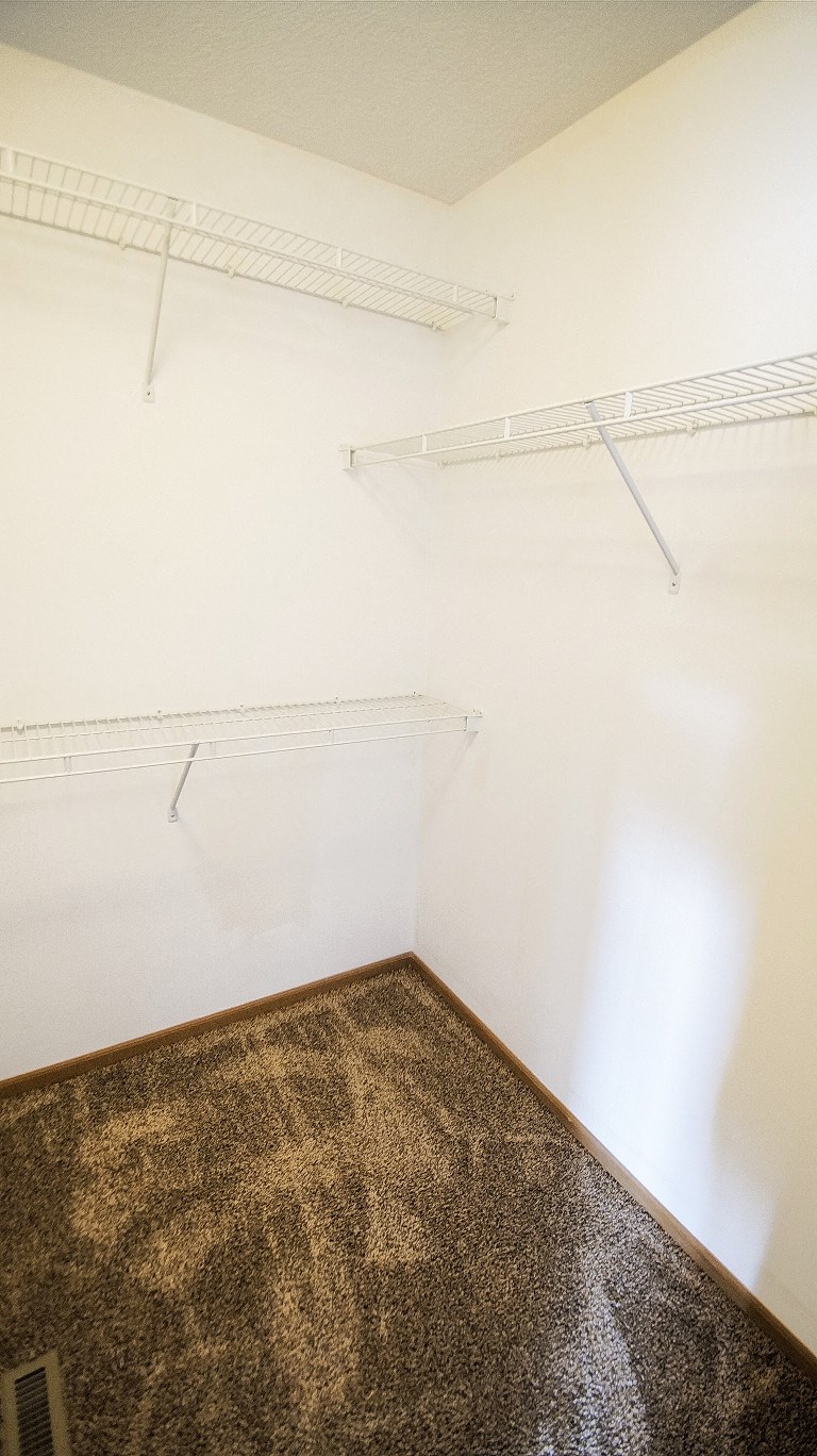 an empty room with shelves on the wall and a carpet