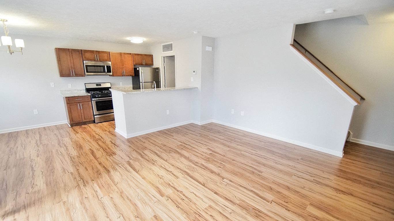 an empty living room and kitchen with wood flooring