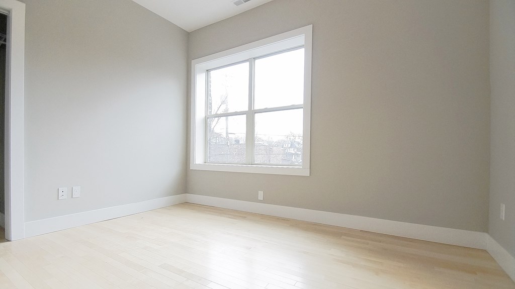 an empty room with a large window and wooden floors