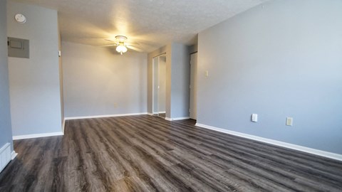 an empty living room with wood flooring and a ceiling fan