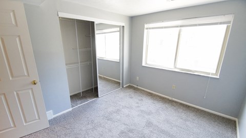 an empty room with a closet and a window